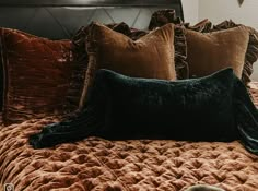 a bed with brown and black pillows on it