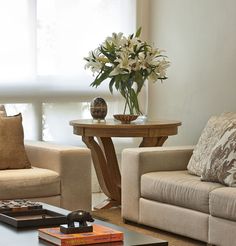 a living room with two couches, a coffee table and a vase on the end table