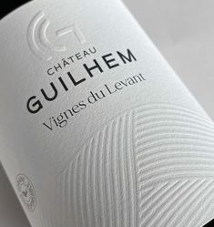 a bottle of wine sitting on top of a white table cloth covered tablecloth with the word gullihem written in black