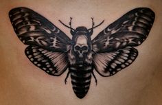 a woman's stomach with a moth tattoo on her belly and skull in the middle