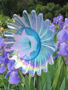 there is a blue glass flower in the middle of purple flowers