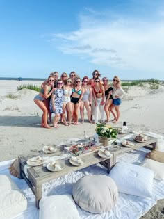 a group of women standing around a table on the beach