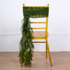 a yellow chair with a green organ draped over it's back on a hard wood floor