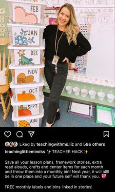 a woman standing next to a stack of books in front of a whiteboard with writing on it