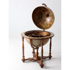 an old fashioned globe on a stand with the lid open to reveal it's contents