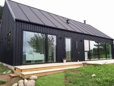 a small black house sitting on top of a lush green field