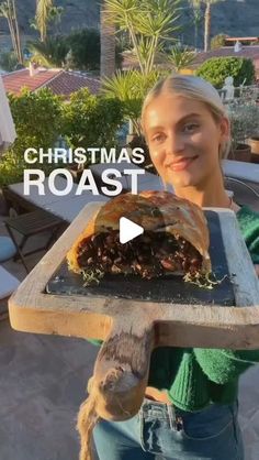 a woman holding a tray with food on it and the words christmas roast in front of her