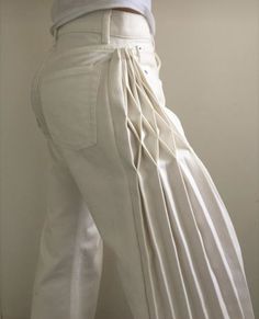 a person wearing white pants with pleating on the bottom, and one leg up