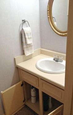 a white sink sitting under a bathroom mirror next to a wooden cabinet and towel rack