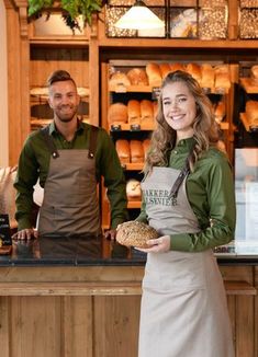 a man and woman standing in front of a bakery counter with bread on the counter