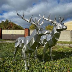 two metal deer sculptures sitting in the grass