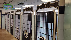 Navy blue dog kennels in a row. The gates are slotted for ventilation and visualization into the kennels. Some of the gates are solid on the bottom to reduce fence-fighting. the rest are fully slotted so the staff can see into the kennels at all times. The gates have a paw print design on them for a bit of decoration. The bone design above the gates is to number each kennel. These kennels are numbered "1, 2, 3, 4, 5." Daycare Business, Dog Kennels, Perfect Face