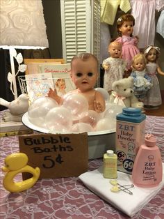 a baby doll in a bathtub surrounded by toys and other items on a table