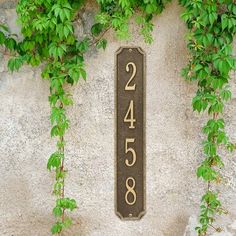 a black and white house number sign on a stone wall with ivy growing around it