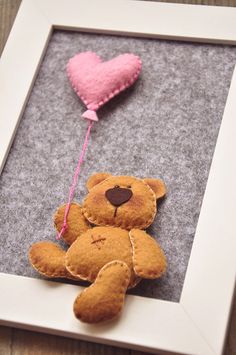 a teddy bear with a heart shaped balloon hanging from it's side in a frame