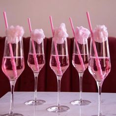 five wine glasses with pink straws in them