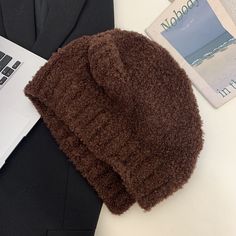 a brown hat sitting on top of a white table next to a laptop computer and magazine