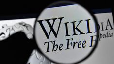 a magnifying glass looking at the logo for wikipedia and the free library website