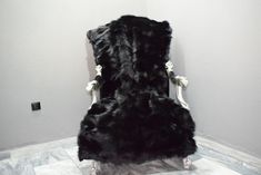 a large black chair sitting on top of a marble floor next to a wall with white trim