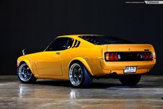 a yellow car parked in a garage next to a black wall