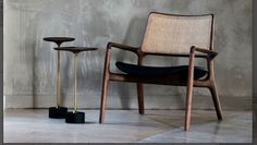 a chair and two stools in front of a wall with concrete walls behind it