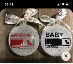 two christmas ornaments with baby loading and grandparents loading labels on them, hanging from a wooden wall