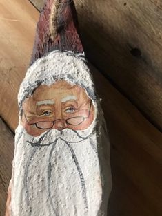 an old man with glasses and a beard is painted on a piece of stone or wood