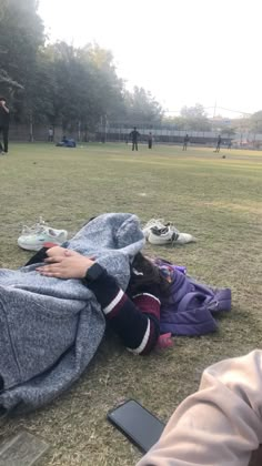 a person laying on the ground with a blanket over their head and other people standing in the background