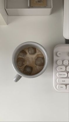 a cup of coffee sitting on top of a white desk next to a calculator