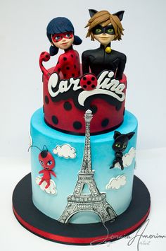 a cake decorated with the eiffel tower and catwoman figurines on top