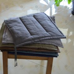 four pillows stacked on top of each other in front of a potted plant and floor