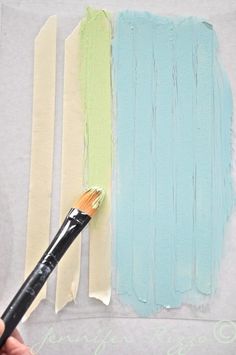 a person holding a paintbrush in their left hand and painting on the wall with different colors