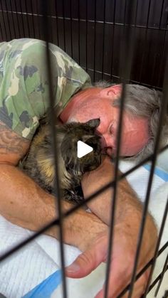 a man sleeping in a cage with his cat