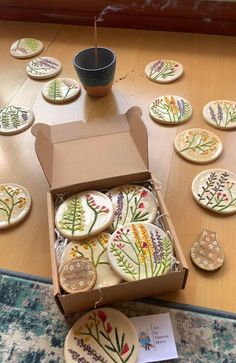 a box full of decorated cookies sitting on top of a table next to a cup