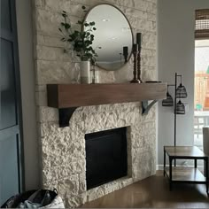 a living room with a stone fireplace and mirror on the mantel above it,