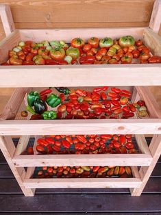 three wooden crates filled with different types of tomatoes and peppers on display in a store