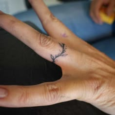 a person's left hand with a small tattoo on the middle finger and an olive branch