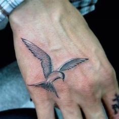 a hand with a bird tattoo on it