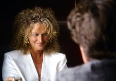 a woman sitting at a table talking to another person