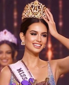 a beautiful young lady wearing a tiara and smiling at the camera with her hands on her head