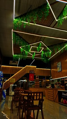 an indoor restaurant with plants hanging from the ceiling and wooden tables in front of it