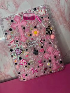 a pink phone case with various stickers and charms on the front, sitting on a counter