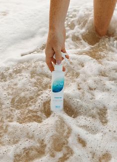 a person is standing in the sand with a bottle on their hand and water coming out of it