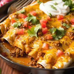 a close up of a plate of enchilada casserole with sour cream