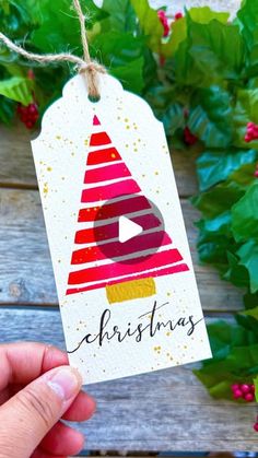 a hand holding up a christmas gift tag