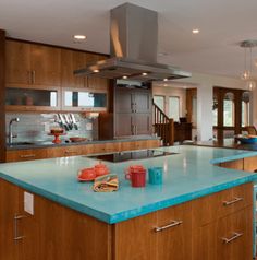 a large kitchen with blue counter tops and wooden cabinetry, along with an island in the middle