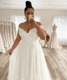 a woman taking a selfie in her wedding dress while looking at her cell phone