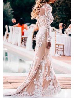 a woman in a long white dress standing next to a pool