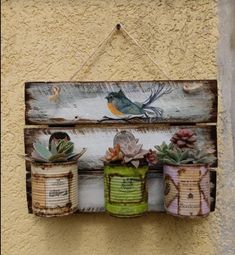 three pots with succulents are hanging on a wooden sign that is attached to a wall