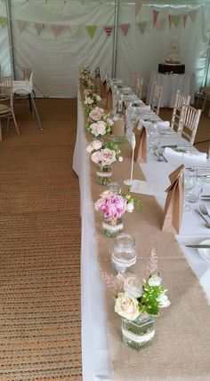 the tables are set up with clear vases and flower centerpieces on them